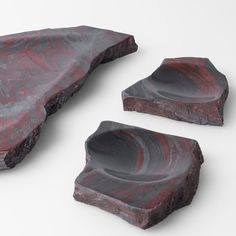 three pieces of art made out of rocks on a white surface with red and black paint