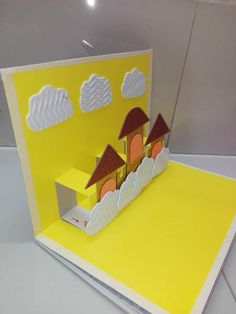 a pop up card with an image of a house in the clouds on it's side