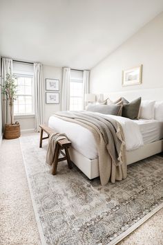 a bedroom with a large bed and rugs on the floor in front of two windows