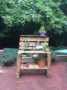 a bench made out of wooden pallets with potted plants and gardening tools on it