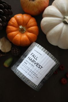 fall harvest candle surrounded by pumpkins and pine cones