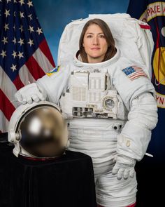 a woman in an astronaut suit standing next to flags