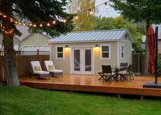 a backyard with a deck, patio furniture and string lights