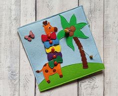 a colorful felt card with giraffes and palm trees on the front side