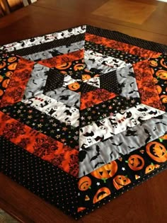 a quilted table topper with pumpkins and jack - o'- lanterns on it