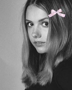 a woman with a pink bow on her head is looking at the camera and has long hair