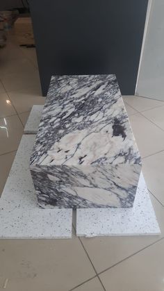 a white and black marble block sitting on top of a tile floor in a room