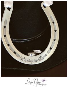 a cowboy hat with two wedding rings on it's brim and the words lucky in love