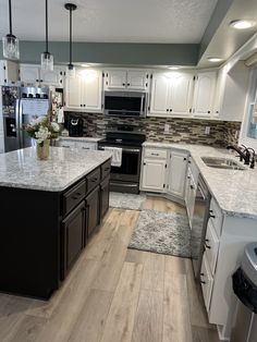 a large kitchen with white cabinets and wood flooring is seen in this image from the front view