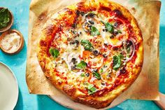 a pizza sitting on top of a wooden cutting board next to some plates and utensils