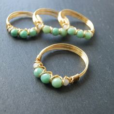 three gold rings with green beads are sitting on a black surface and one is in the middle