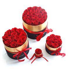 three round boxes with roses in them on a white surface, one is open and the other two are closed