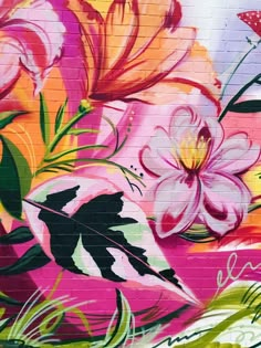 a colorful mural painted on the side of a brick building with flowers and leaves around it