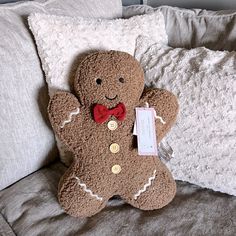 a brown teddy bear sitting on top of a bed next to pillows and a tag