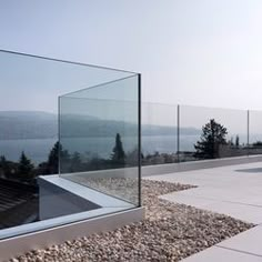 there is a glass wall on the roof of this building that overlooks water and mountains