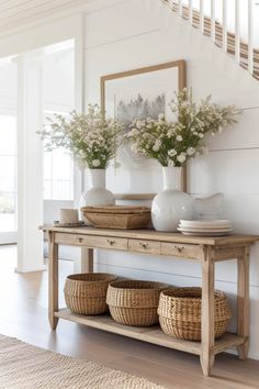 a wooden table topped with baskets and vases next to a stair case filled with flowers