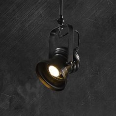 an old fashioned light hanging from the ceiling in a dark room with concrete flooring