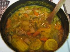 a pot filled with meat and vegetables on top of a stove next to a wooden spoon