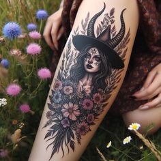 a woman with horns and flowers on her thigh is sitting in the grass next to wildflowers