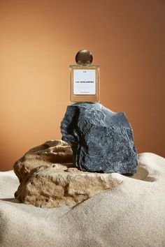 a bottle of perfume sitting on top of a rock next to a large rock with a sign