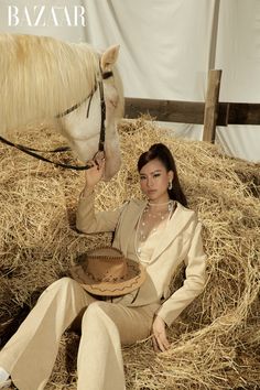 a woman sitting on the ground next to a horse