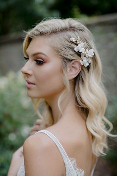 a woman with blonde hair wearing a white dress and flower in her hair is looking off to the side