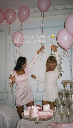 two women in white dresses holding pink balloons