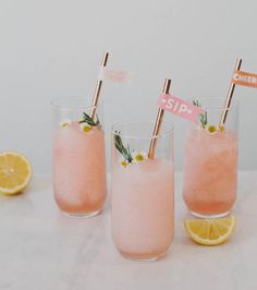 three glasses filled with pink lemonade and topped with strawberries on the rims