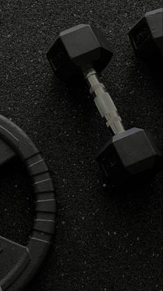 two black dumbbells sitting next to each other on the ground