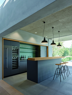 an open kitchen with two stools next to the counter and wine bottles on the shelves