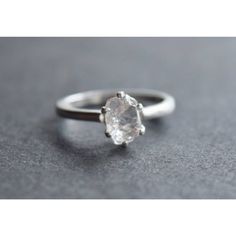 a white diamond ring sitting on top of a gray surface with the center stone in the middle