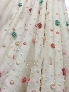 some white fabric with pink and green flowers on the top, along with other material