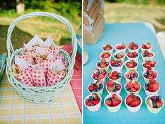 strawberries and other fruit are in cups on the table next to a basket full of strawberries