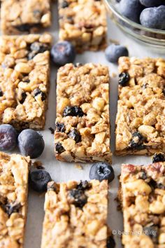 blueberry granola bars cut into squares and placed next to a bowl of blueberries