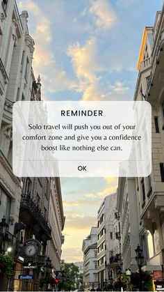 a city street with tall buildings and a quote on the side that reads reminder solo travel will push you out of your comfort zone and give you a