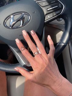 a woman's hand on the steering wheel of a car with her nails painted white