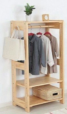 a wooden shelf with clothes hanging on it and a basket in the corner next to it