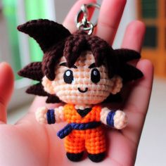 a hand holding a small crocheted keychain in the shape of a cartoon character