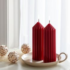 three red candles sitting on top of a white plate next to some chocolate covered balls