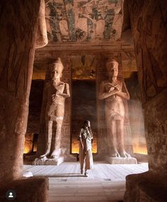 a woman standing in front of two statues at the egyptian museum, with another statue behind her