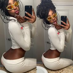 a woman in white pants and yellow sunglasses taking a selfie with her cell phone