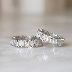 three diamond rings sitting on top of a white counter next to each other, with one being cut in half