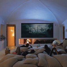 two people laying on bean bag chairs in front of a harry potter movie poster and fireplace