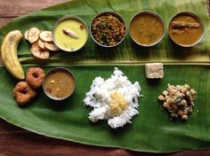 a banana leaf with several different types of food in small bowls on it, along with other foods