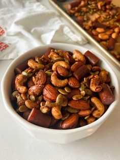 a bowl filled with nuts next to a tray of other nuts on a counter top