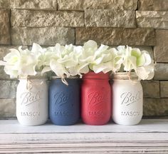 three painted mason jars with flowers in them