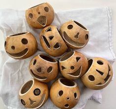 a pile of wooden bowls with faces painted on the sides and holes in the middle