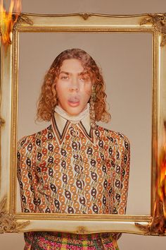 a woman with curly hair is holding up a framed photograph in front of her face