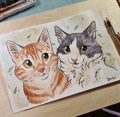 a drawing of two cats sitting next to each other on a table with markers and pencils