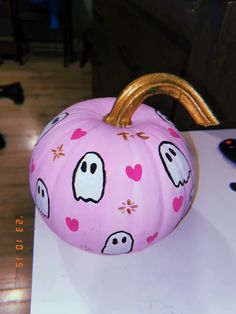 a pink pumpkin decorated with ghost faces and hearts